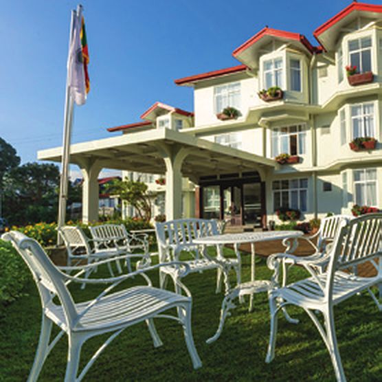 Galway Heights Hotel: a white colonial-style building with red gabled roofs, lawns and white garden furniture under a blue sky