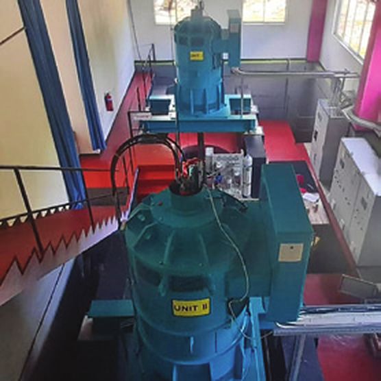 A blue turbine generator inside the Hapugahakumbura hydro power station, with red railings and stairs
